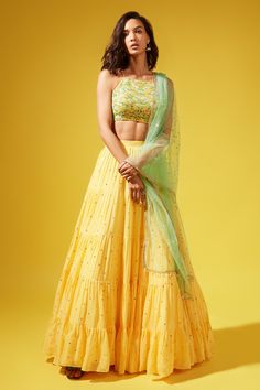 Yellow georgette tiered lehenga with all-over embroidered motifs and gathered detailing. Paired with halter neck silk embroidered blouse and tulle dupatta with bead tassel detailing at hem.
Component: 3
Pattern: Embroidered
Neckline: Halter neck
Sleeve Type: Sleeveless
Fabric: Lehenga: Georgette, Blouse: Silk, Dupatta: Tulle
Color: Yellow
Other Details: 
Open back blouse
Criss-cross tie-up at back
Tasseled hem dupatta
Occasion: Mehendi and Haldi - Aza Fashions Yellow Skirt Outfit Indian, Haldi Outfits For Bridesmaid, Haldi Outfit, Yellow Lehenga, Green Tulle, Fabric Skirt, Blouse Silk, Backless Blouse, Georgette Blouse