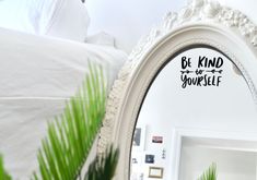 a white mirror sitting on top of a table next to a potted palm tree