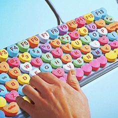 a hand is typing on a keyboard made out of colorful letters and small magnets