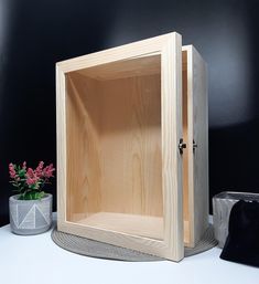 a wooden box sitting on top of a white table next to a potted plant