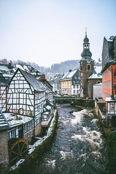 a river running through a small town surrounded by tall buildings with steeples on top