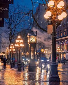 a city street at night with lights on and a clock tower in the middle of it