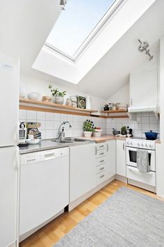 a white kitchen with skylight above the stove and dishwasher on the counter