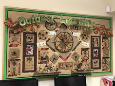 a bulletin board with pictures and words on it that says outdoor learning, located in front of two computer monitors