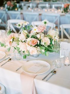 the table is set with white and pink flowers