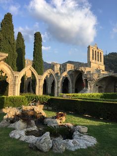 an old building with trees and rocks in the foreground, surrounded by greenery