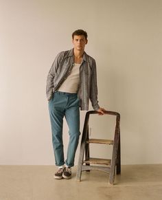 a man standing next to a wooden step stool in front of a white wall,