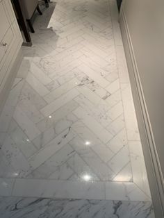 a bathroom with white marble flooring and herringbone pattern on the wall next to the toilet