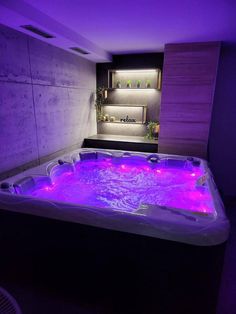 an indoor hot tub with purple lights in the room