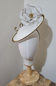 classic white, handmade saucer fascinator. Embellished with a wire, netted, white and gold rose. Sinamay base, white and trimmed with a gold brim. Gold swirl decoration.  Secured to the head with a white satin hairband and hidden mini comb. Sinamay is a natural fibre derived from the banana plant. White Costume Hat With Round Crown For Parties, White Adjustable Costume Hat With Pinched Crown, White Pinched Crown Hat For Royal Ascot, White Hat With Pinched Crown For Royal Ascot, White Hats For Royal Ascot Event, White Pinched Crown Costume Hat For Party, White Party Hat With Round Crown, White Costume Hat With Pinched Crown For Party, White Costume Hats For Royal Ascot