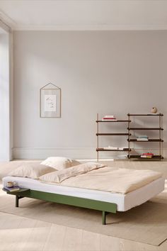 a bed sitting on top of a wooden floor next to a book shelf