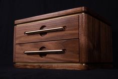 a wooden box with two brass handles on a black background in front of a dark backdrop