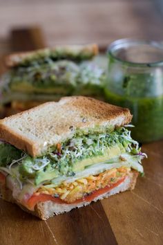 a cut in half sandwich sitting on top of a wooden cutting board next to a jar