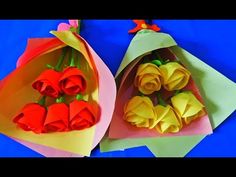 two paper bags with flowers in them on a blue surface