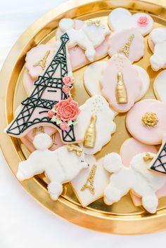 decorated cookies in the shape of eiffel tower on a gold platter with pink and white frosting