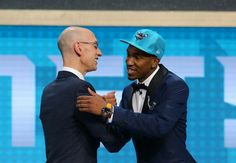 two men in suits and blue hats are talking to each other while one man holds his arm around the other's shoulder