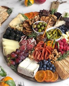 an assortment of cheeses, crackers and fruits are arranged on a platter