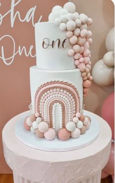 a white and pink cake with balloons on top