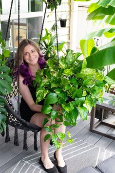 a woman is sitting on a swing with some plants