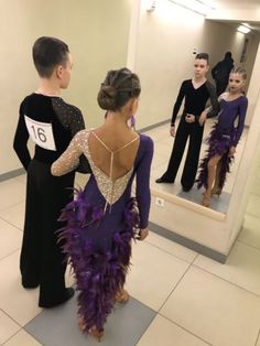 a group of young people standing in front of a mirror wearing purple and black outfits