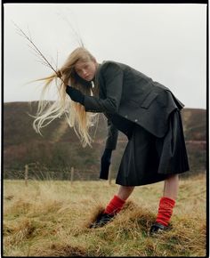 a woman with long blonde hair and red socks is bending over to pick up some dry grass