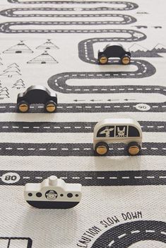 three little cars are on the road in front of each other, and one is black and white