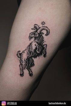 a black and white photo of a goat tattoo on the leg, with stars around it