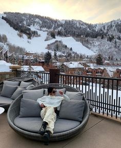 a man sitting on top of a gray couch next to a snow covered mountain range