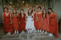 a group of women standing next to each other in orange dresses and white tennis shoes