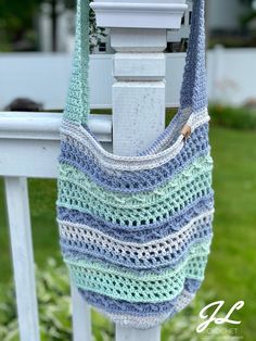 a crocheted bag hanging on the side of a white fence