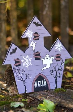 a purple house with halloween decorations on the roof and windows is sitting in the woods