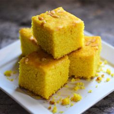 three pieces of yellow cake sitting on top of a white plate with some nuts around it