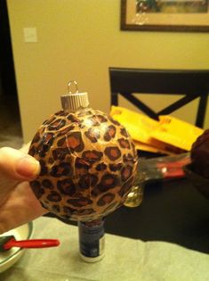 a person is holding a christmas ornament in front of a dining room table