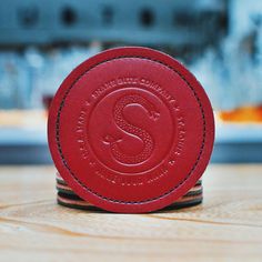 a red leather coaster sitting on top of a wooden table