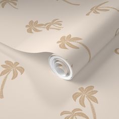 a white and gold wallpaper with palm trees on the side, next to a roll of paper