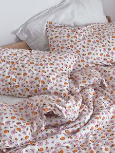 an unmade bed with white sheets and orange polka dots on the comforter is shown