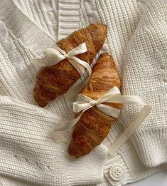 two croissants wrapped in white ribbon on top of a sweater