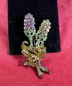 Lovely rhinestone brooch with a pink and white flowers with green stems and a green and orange leaf, on a silver base. Light wear on the back.  2 ¾" x 1" Green Jeweled Brooch For Gift, Green Jeweled Brooches As Gift, Green Flower Brooch Pins, Green Flower Shaped Brooch Pins, Green Flower-shaped Brooch Pins, Spring Green Brooch Gift, Green Spring Brooches As Gifts, Green Spring Brooches Perfect As A Gift, Green Spring Gift Brooches