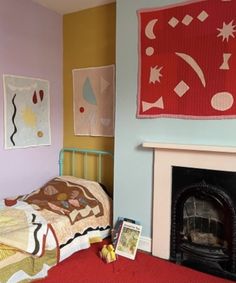 a bed room with a neatly made bed next to a fire place and paintings on the wall