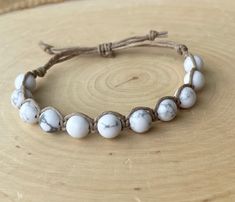 a bracelet with white marble beads on a wooden surface