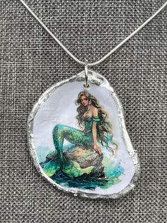 a mermaid sitting on top of a rock with her tail hanging from it's back