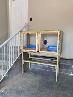 a bird cage sitting on top of a wooden table next to a stair case and door