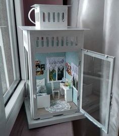 a doll house is shown in the window sill, with its door open to reveal it's bedroom