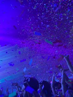 confetti falling from the ceiling at a party with people holding up cell phones