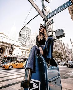 a woman sitting on the back of a blue car in front of a street sign