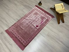 a pink rug sitting on top of a hard wood floor next to a wooden table