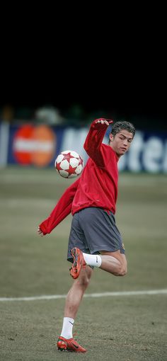 a man kicking a soccer ball on top of a field