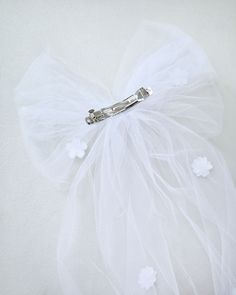 Long oversized style tulle bow topped with scattered flower applique that is placed carefully by hand and attached on a barrette hair clip. Perfect for wedding, communion, birthday parties or any special events. DETAILS:Colors available: White and IvorySize: W 9", L 18" Handmade in the USA White Bow Hair Accessory For Wedding, White Decorative Bow Hair Accessories For Summer, White Bow Hair Accessories For Gifts, Cute White Hair Accessories With Pink Bow, White Bow Hair Clip, Tulle Bows, Bow Shoes, Glitter Bow, Oversized Style