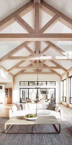 a living room filled with lots of furniture and wooden beamed ceiling beams in an open floor plan