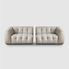 two white leather couches sitting next to each other on a gray background, one is facing the camera